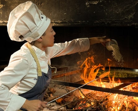 Female chef cooks food a over grapevine wood fire at a restaurant