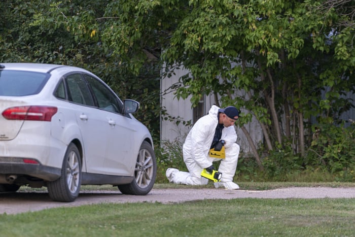 An investigator in protective equipment looks onto the ground at a crime scene in Weldon.