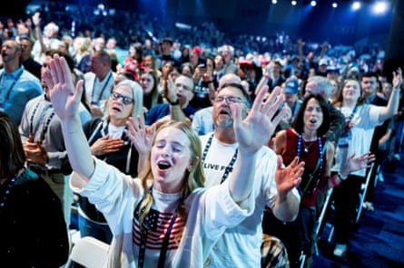 people in crowded auditorium lift up hands and sing people in crowded auditorium lift up hands and sing