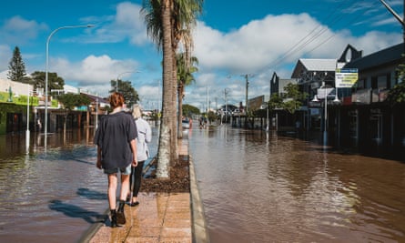 People walking down the middle of a flooded Ballina street