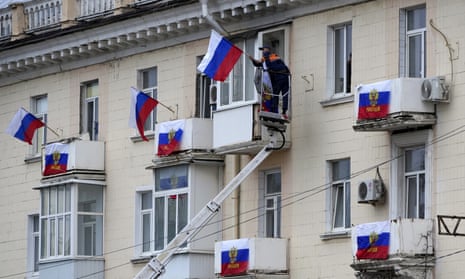 Workers hang Russian flags at an apartment building in Luhansk, eastern Ukraine