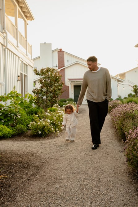 A father and daughter hold hands as they walk down a path on a warm sunny day.