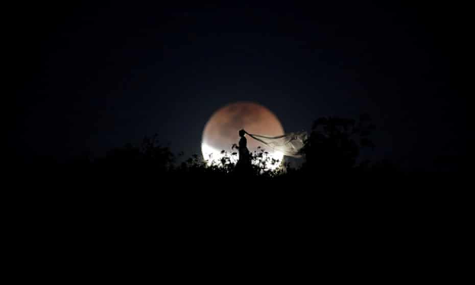 A bride poses for photo during a total lunar eclipse from in Brasilia, Brazil, July 27, 2018.