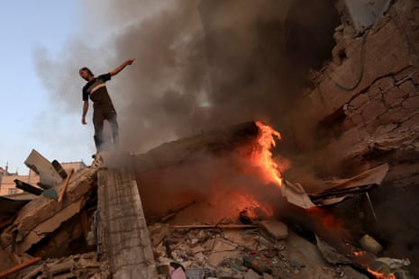 A Palestinian man gestures as he stands on the rubble of a collapsed building as a fire burns following a strike by the Israeli military on Khan Yunis in the southern Gaza Strip on November 4 , 2023, amid the ongoing battles between Israel and the Palestinian group Hamas.