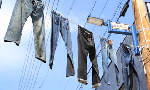 Five pairs of Jeans hanging on washing lines across a street.