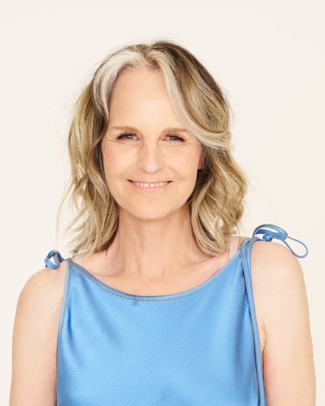 Helen Hunt in a blue silk dress with shoulder ties smiles at the camera against a pale background
