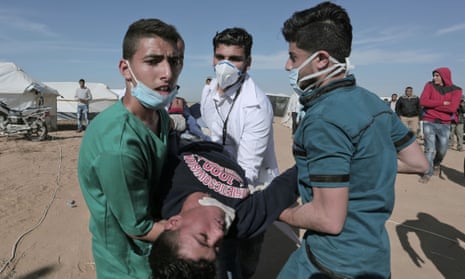 Palestinian paramedics carry a protester injured during clashes with Israeli forces at the Israel-Gaza border, 2 April 2018. 