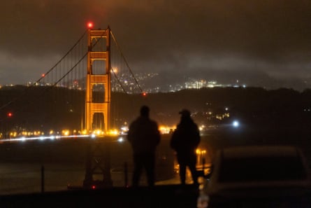 silhouettes of people looking at bridge in the dark