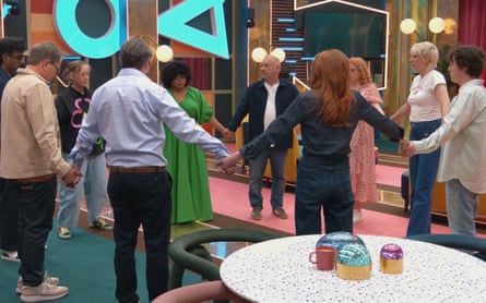 The contestants stand in a circle holding hands