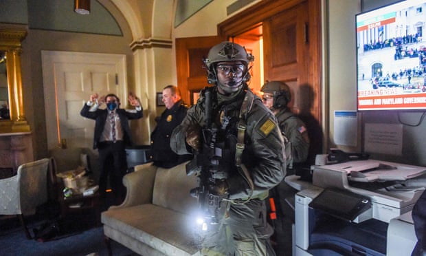 A Congress staffer holds his hands up while a Swat team secures an area in the Capitol building