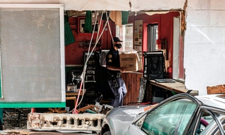 A member of the New Orleans police department carries a box of food out of a damaged restaurant.