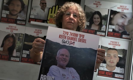 Aviva Siegel holds up a poster of her husband Keith with images of other hostages behind her