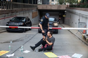 a police officer stands over a person seated on the ground