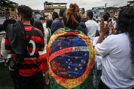 Woman with Brazil’s green and yellow flag over her shoulders, stained with red paint.