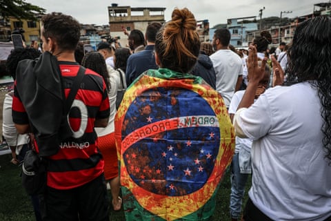 Woman with Brazil’s green and yellow flag over her shoulders, stained with red paint. dqxikeidqkikdinv