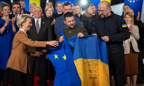 Ukraine's President Volodymyr Zelensky (C), European Commission President Ursula von der Leyen (C-L) and Ukraine's Prime Minister Denys Shmyhal (C-R) holding the EU and Ukrainian flags