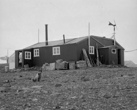 A black-and-white image of a wooden hut on a hill