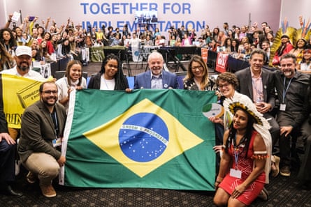 People smile and hold a Brazilian flag
