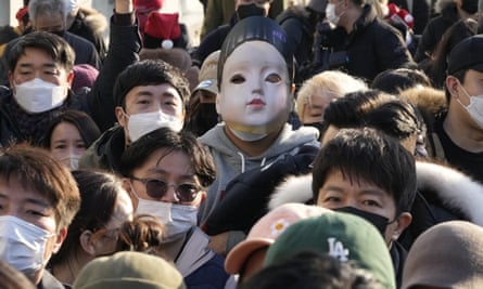 A man wears a mask depicting Younghee, a doll from the Netflix series Squid Game, during a rally in Seoul.