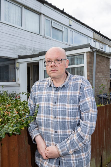 A man standing outside a house and leaning on a fence