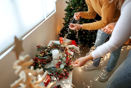 A couple decorating for Christmas with string lights