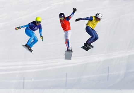 Charlotte Bankes (right) takes the final jump in the lead ahead of Italy (left) and France (centre) to win gold with her team-mate Huw Nightingale in the mixed snowboard cross.