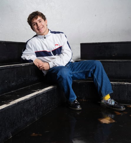 Browne in a track suit top and jeans leaning on a piano