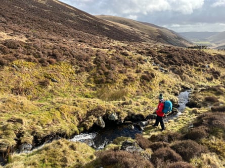 Woman with backpack fording a stream