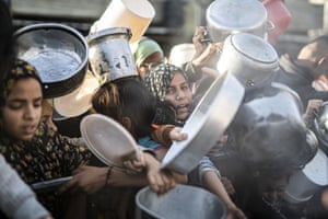 Palestinians queue to receive food distributed by aid organisations in Rafah