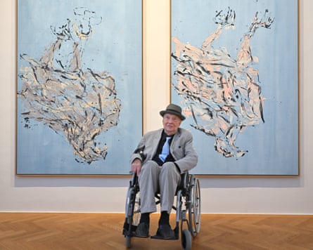 Georg Baselitz sitting in a wheelchair in front of two upside-down paintings
