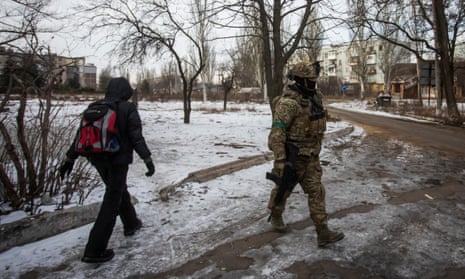 A resident walks past a Ukrainian serviceman on a street the frontline town of Bakhmut