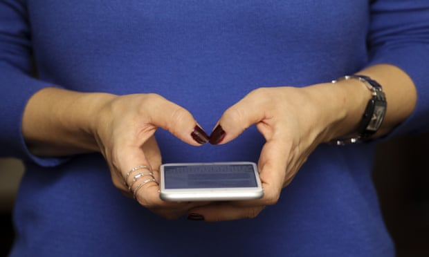 Close up of woman in blue jumper holding a smart phone