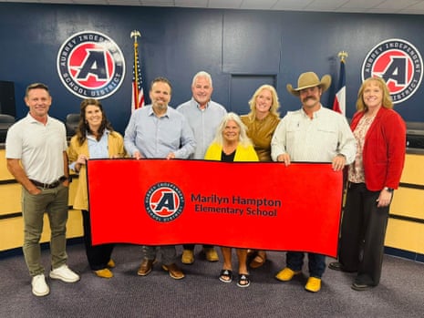 Group poses holding a red banner naming Marilyn Hampton elementary school