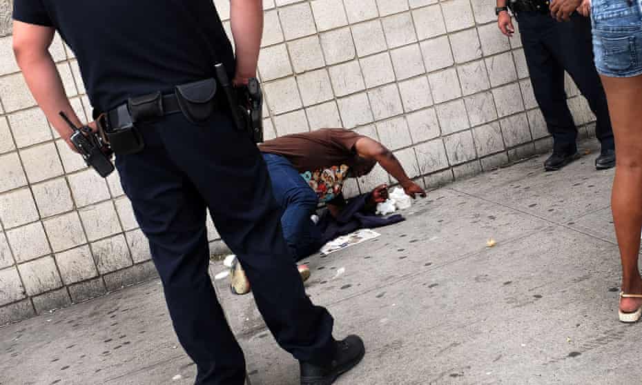 Police stand over a man passed out due to ‘synthetic marijuana’ in East Harlem in September.