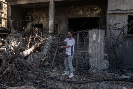 A man handles electric cables outside a heavily damaged building.