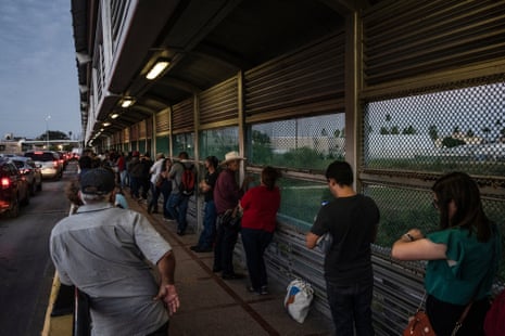 People stand in a queue at a border crossing outside