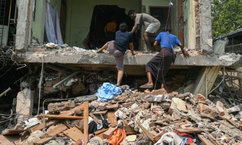 People climb into a damaged building as they look for survivors in Mandalay.