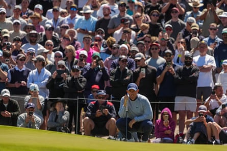The gallery looks on as Rory McIlroy reads the green on the fifth hole