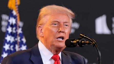 Donald Trump speaking into a microphone with a US flag behind him