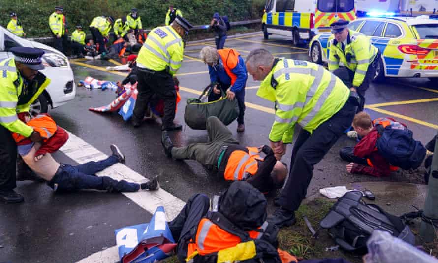 Police officers detain protesters from Insulate Britain at a roundabout in London