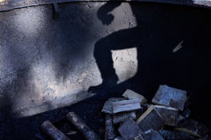 Silhouette of a man standing near a pile of burnt charcoal