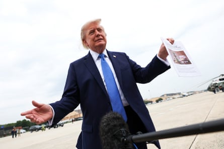 Man in suit on tarmac holds print-out.