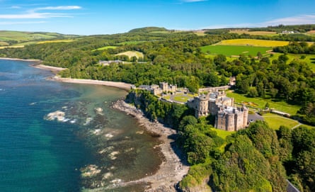 A castle on coast surrounded by trees on a bright sunny day.