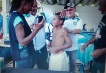 The young player receives a trophy at Pequeninos do Meio Ambiente.