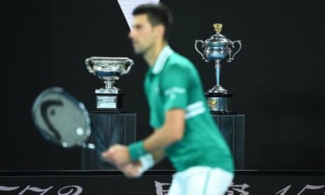 The Norman Brooks Challenge Cup and the Daphne Akhurst Memorial Cup are seen behind Djokovic as he closes in on victory.