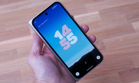 The Google Pixel 9 Pro Fold held in a hand showing the lockscreen while the phone is shut.