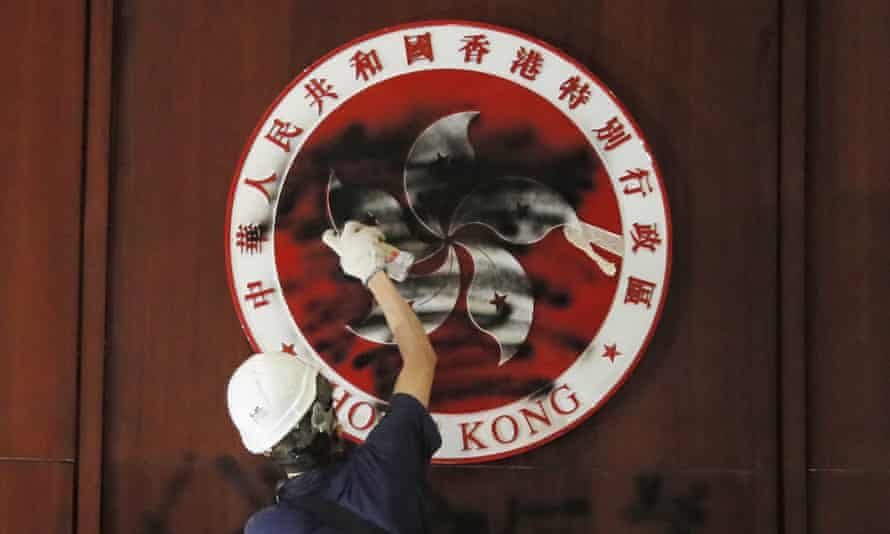 A protester defaces the Hong Kong emblem