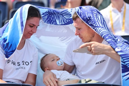 A couple try to cool down their baby while watching the women’s park cycling BMX freestyle qualifiers