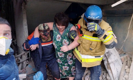 Rescue workers help a woman leave a residential building damaged after a strike in Zaporizhzhia, Ukraine