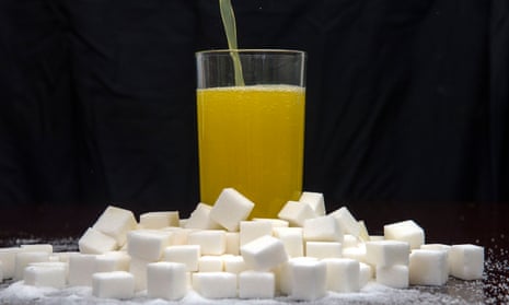 An orange carbonated drink surrounded by sugar cubes.